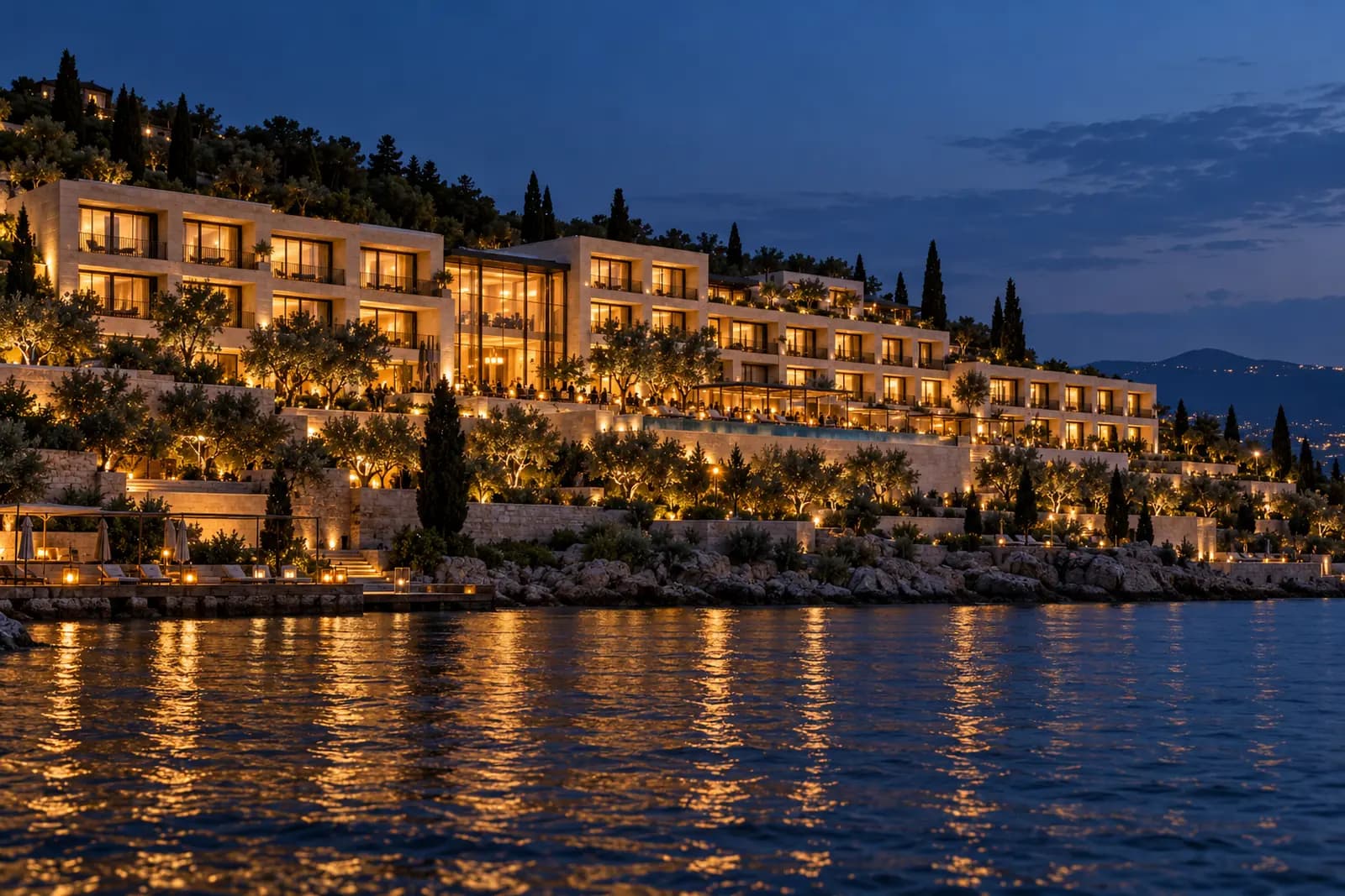 Mavi saatte su kenarında, bütün pencereleri aydınlık teraslı bir otel.